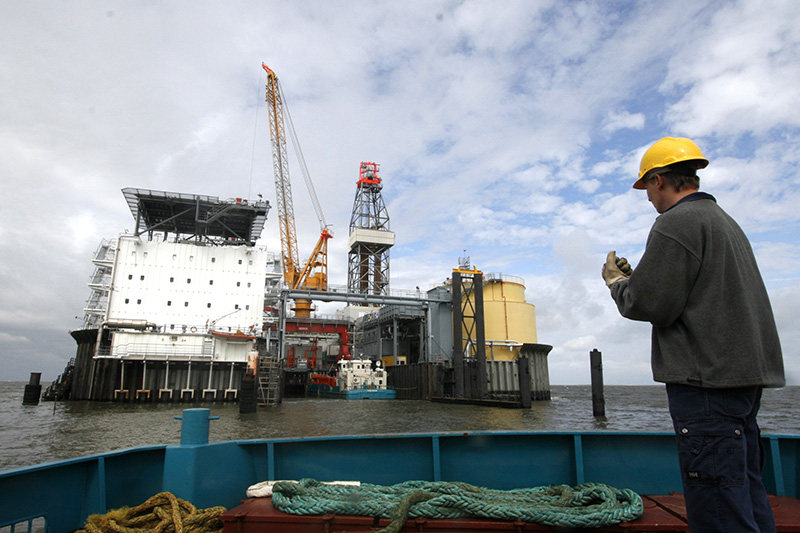 A worker prepares to dock with a support ship at the artificial Mittelplate drilling and production island for oil in the Wattenmeer tidelands off the coast of the German state of Schleswig-Holstein noth-west of Cuxhaven