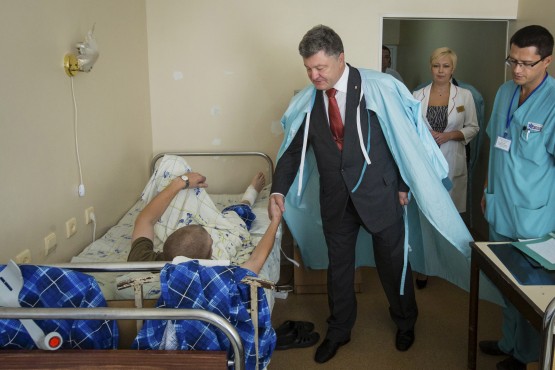 Ukrainian President Poroshenko shakes hands with serviceman who was wounded during Monday's protest outside parliament building, at Ukrainian Interior Ministry's hospital in Kiev